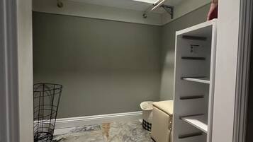 A walk-in closet with a marble floor, a white shelving unit, and a metal rack.