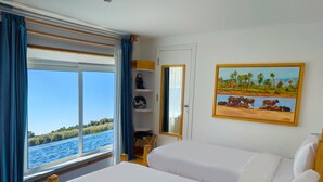 Una stanza con una grande finestra, un letto, uno scaffale con oggetti decorativi e un quadro appeso al muro.