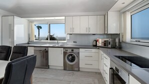 Cocina moderna con lavadora integrada, un amplio ventanal con vistas y un comedor con sillas.