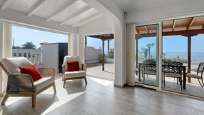 Un amplio balcón con vistas al mar, mobiliario de mimbre y una decoración moderna.