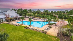 Ein Resort mit Schwimmbad, Liegestühlen und Blick auf den Ozean bei Sonnenuntergang.