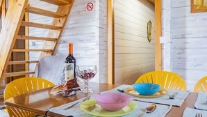 Puinen sisustus, jossa on ruokapöytä kahdelle, viinipullo ja lasi.