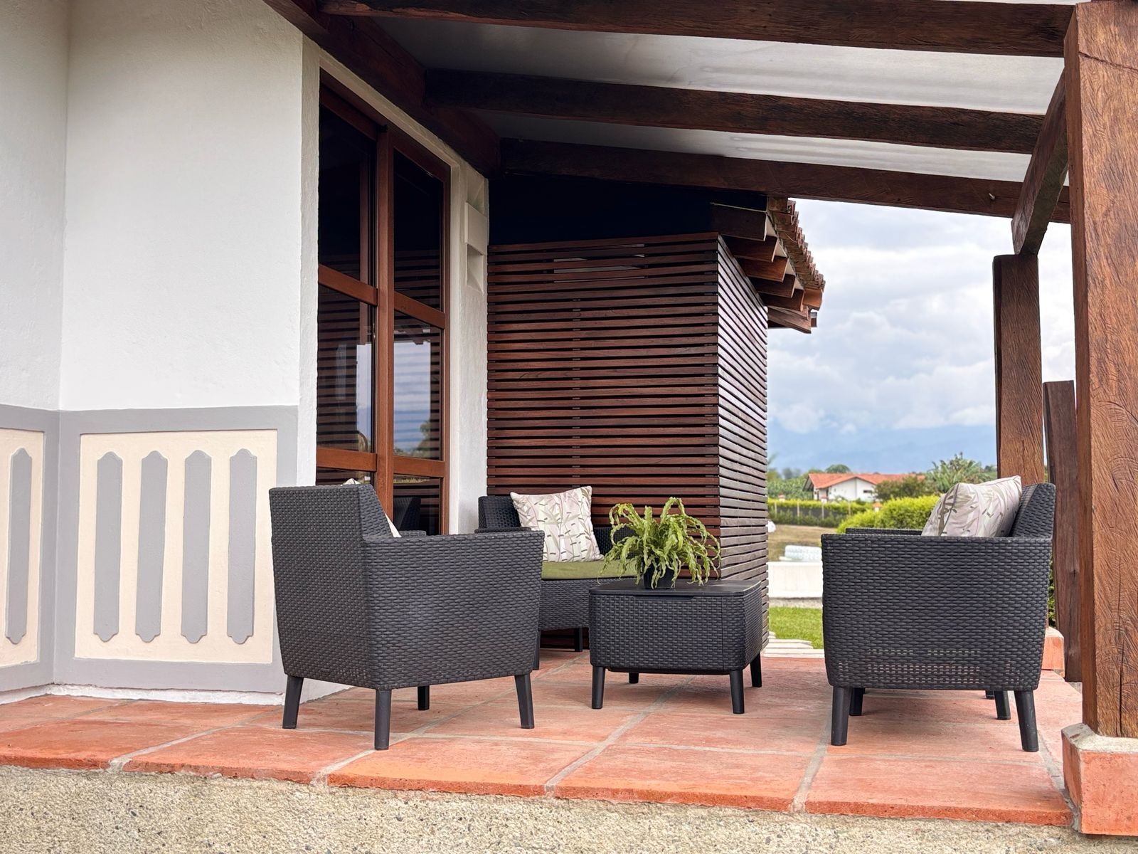 An outdoor seating area with wicker furniture and a potted plant.