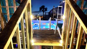 A wooden staircase leading to a pool area with a caution sign. - Sunset By The Sea 3054 - FMB (Fort Myers Beach)
