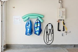 Een kamer met een brandblussingsput, twee blauw-wit gestreepte tassen aan de muur en een boiler met slangen.