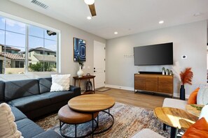 Un salon moderne avec un canapé, une table basse et un téléviseur à écran plat fixé au mur.