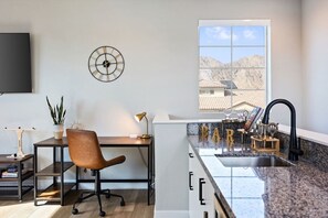 A modern kitchen with a granite countertop, a sink, and a window with a view of mountains.