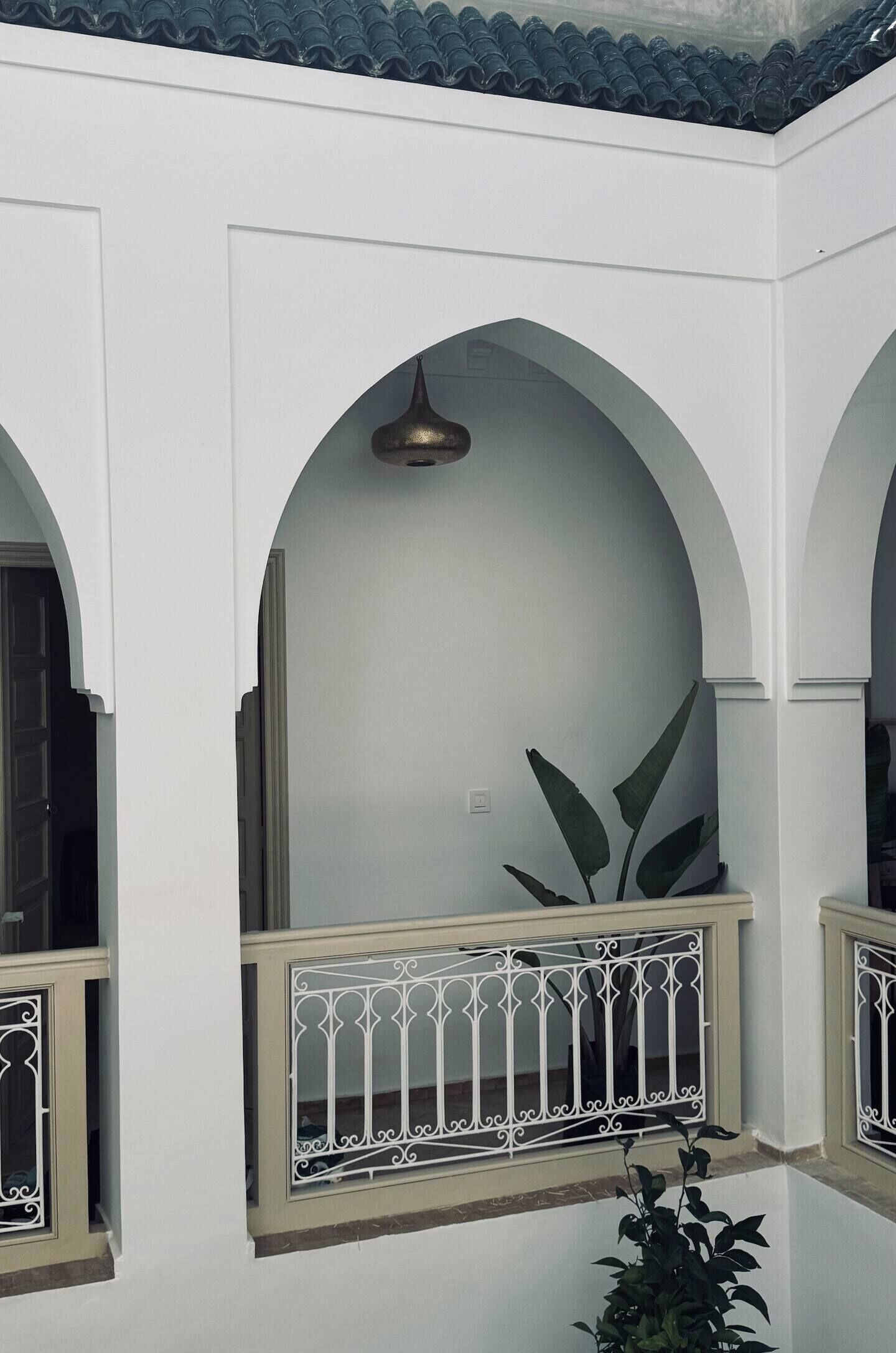 Un bâtiment blanc doté de fenêtres en arc de cercle et d’un balcon orné d’une rambarde en métal.