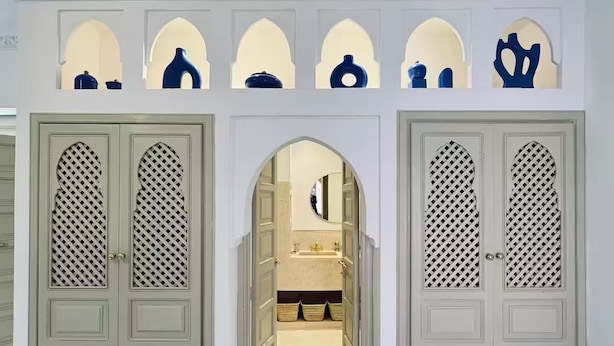 A hallway with two symmetrical doors, each with a decorative archway and a patterned lattice design. - À l'ombre des orangers - "Touareg". (Marrakesh)