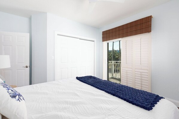 Un dormitorio con una cama, una puerta y una ventana con persianas.