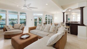 A spacious living room with a large sofa set, a coffee table, and a dining area with a table and chairs. - Welcome to Bluefin – Your Waterfront Getaway! (Treasure Island)