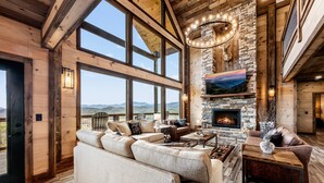 Un salón espacioso con un sofá grande, una chimenea y vistas a las montañas.