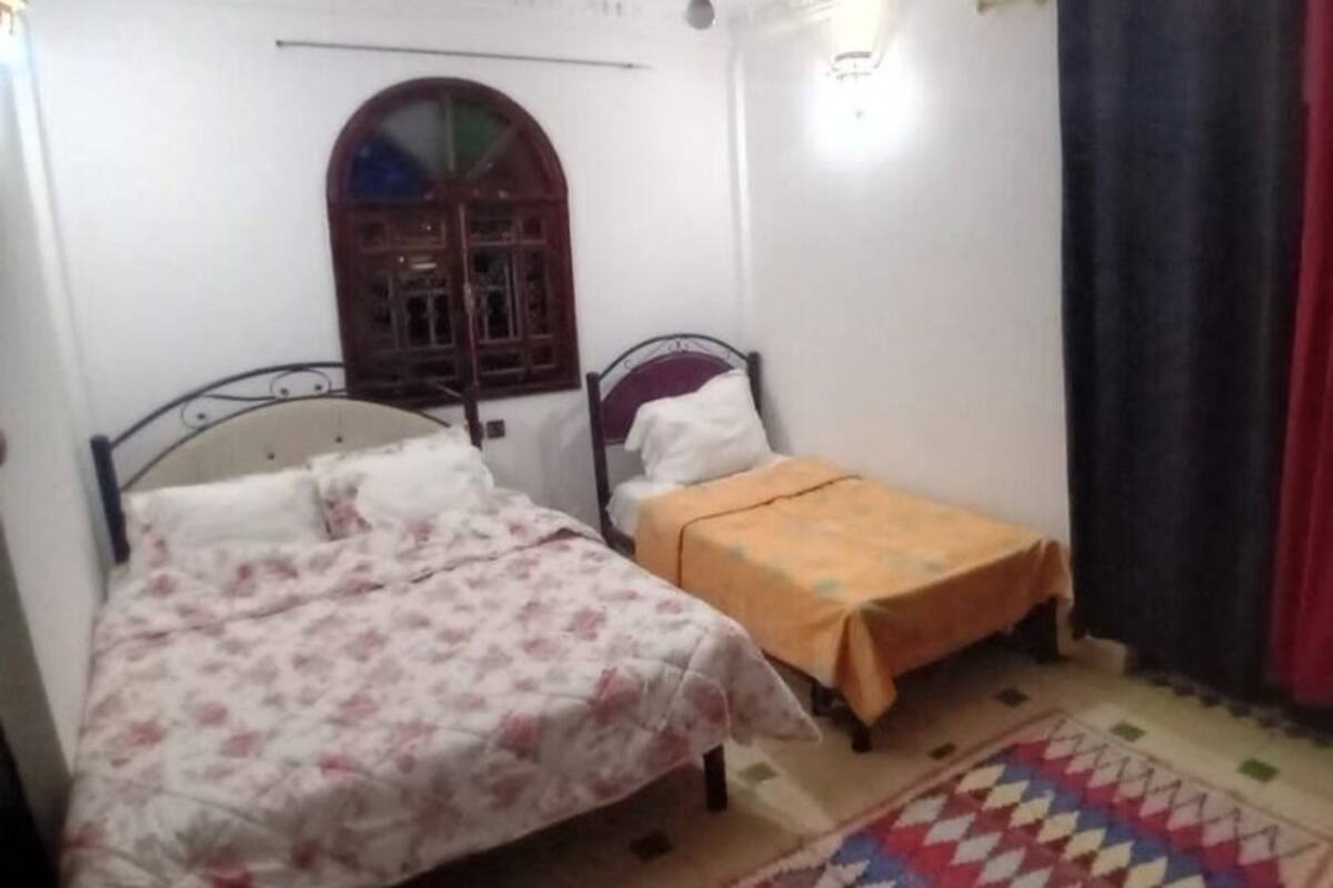 Une chambre avec deux lits, une fenêtre et un rideau rouge.
