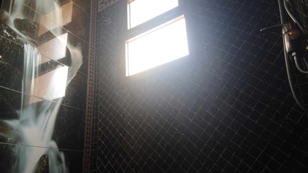 A shower area with a tiled wall and a window.