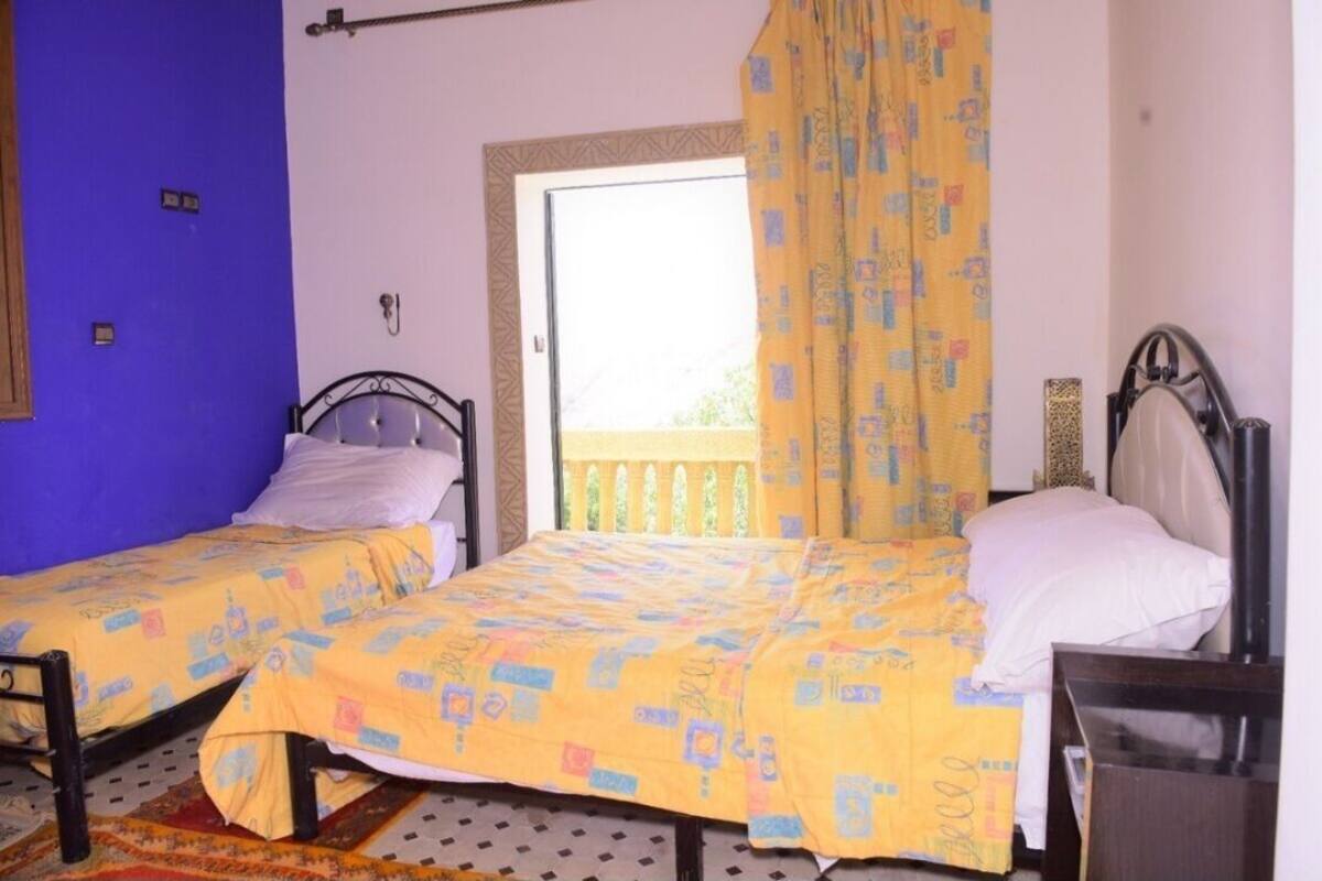 Une chambre avec deux lits, une fenêtre donnant sur un paysage agréable et une porte.