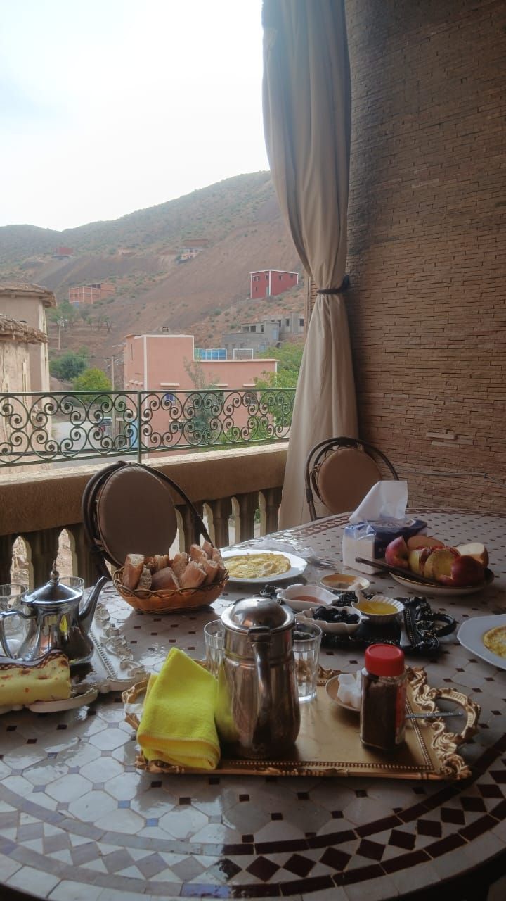 A dining table with various dishes and utensils, set against a view of a hilly landscape.