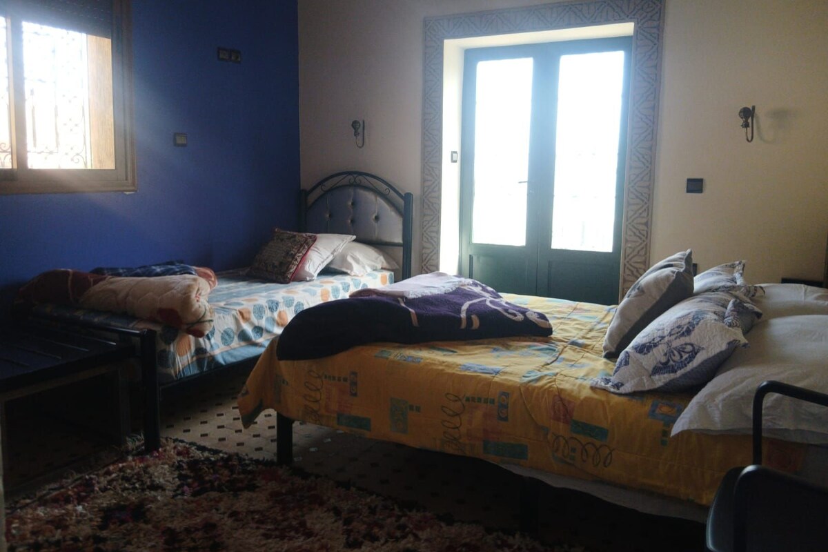 Una habitación con dos camas, una ventana y una puerta.
