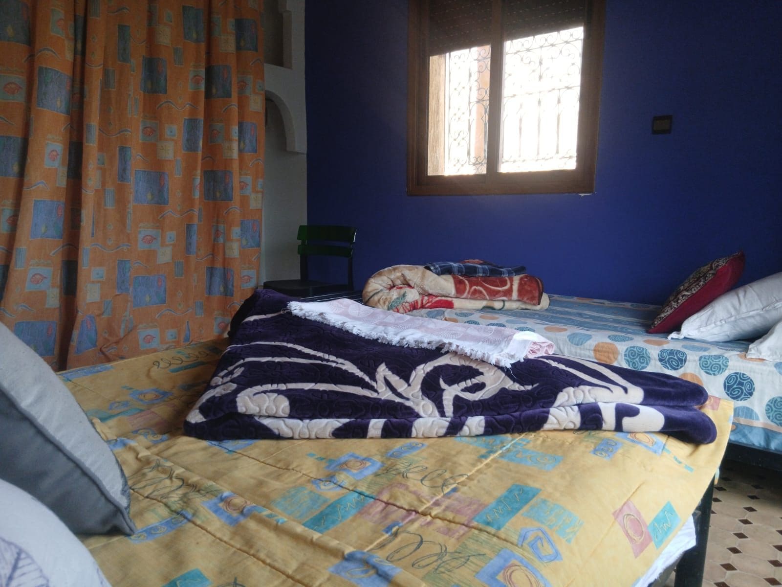 Una habitación con cama, una silla y una ventana.