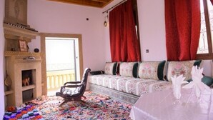 Una habitación acogedora con techo de madera, un sofá tapizado con motivos florales, una alfombra estampada y una silla.