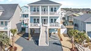 Una propiedad frente al mar de varios pisos con una escalera central, balcones y un área de piscina.