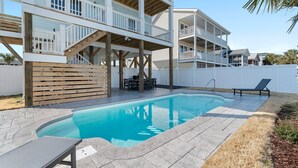 Un edificio de dos pisos con piscina, mobiliario exterior y terraza de madera.