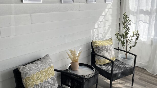 A room with two wicker chairs, a small table, and a potted plant. There are framed welcome signs on the wall. - Black sheep cottage!
Charming 1 bedroom cottage in peaceful West Allis (West Allis)