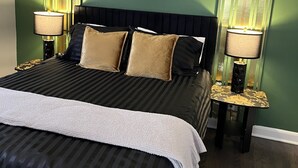 A bed with a black and white striped bedspread, two gold-framed lamps, and a framed floral artwork on the wall. - Black sheep cottage!
Charming 1 bedroom cottage in peaceful West Allis (West Allis)