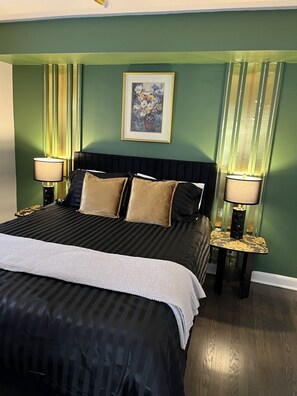 A bed with a black and white striped bedspread, two gold-framed lamps, and a framed floral artwork on the wall. - Black sheep cottage!
Charming 1 bedroom cottage in peaceful West Allis (West Allis)