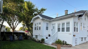 A two-story white house with a front porch, a covered patio area, and a well-maintained lawn. - Black sheep cottage!
Charming 1 bedroom cottage in peaceful West Allis (West Allis)