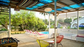 A covered outdoor area with a pool, lounge chairs, and a foosball table. - Cool Villa Guest House (Sekondi-Takoradi)
