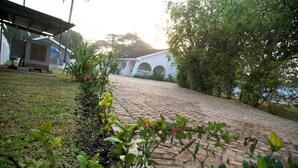 A paved pathway leading to a white building with arches, surrounded by greenery and a body of water. - Cool Villa Guest House (Sekondi-Takoradi)