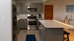 A modern kitchen with stainless steel appliances, grey cabinets, and a wooden floor. - LakePointe Shores #4 -Beautiful cottage Madison on the Lake (Madison)