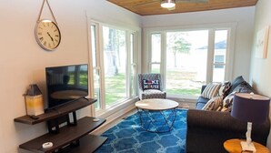 A living room with a TV, sofa, coffee table, and a rug. - LakePointe Shores #4 -Beautiful cottage Madison on the Lake (Madison)