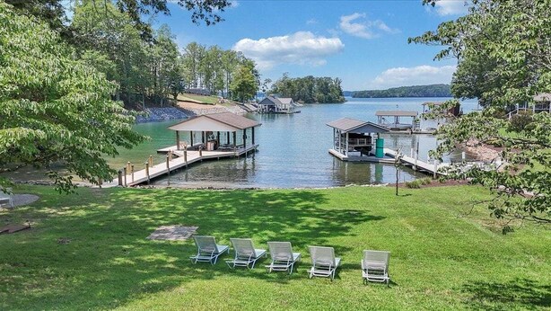 A lakeside property with docked boats, a grassy lawn, and lounge chairs. - Kelly Kove - Beach Area Sleeps 14, Private Dock, Pet Friendly (Penhook)