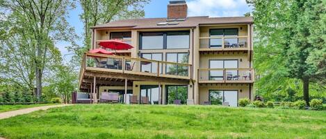 A multi-story building with a covered outdoor seating area and a grassy lawn.