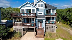A two-story house with a balcony on each floor, a front door, and a small front porch. - Oceanside, Close to Beach, Hot Tub- OS5H, Long Beach Day (Corolla)