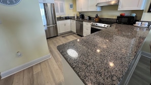 A modern kitchen with granite countertops, stainless steel appliances, and white cabinetry. - WELCOME TO THE IVORY TOWER AT ARCADIAIN SHORES - 2 BEDROOM - CONDO ON THE OCEAN (Myrtle Beach)