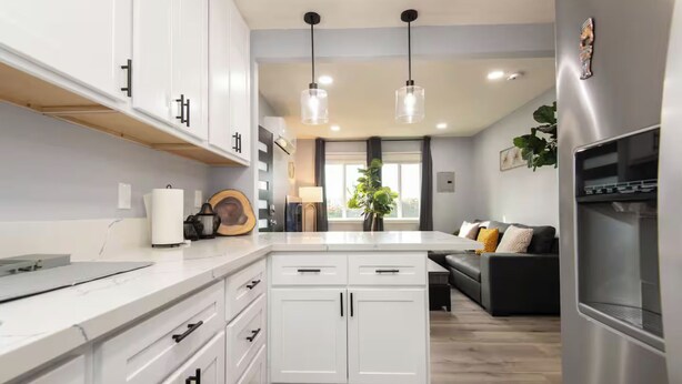 A modern kitchen with white cabinets, a central island, and pendant lighting.
