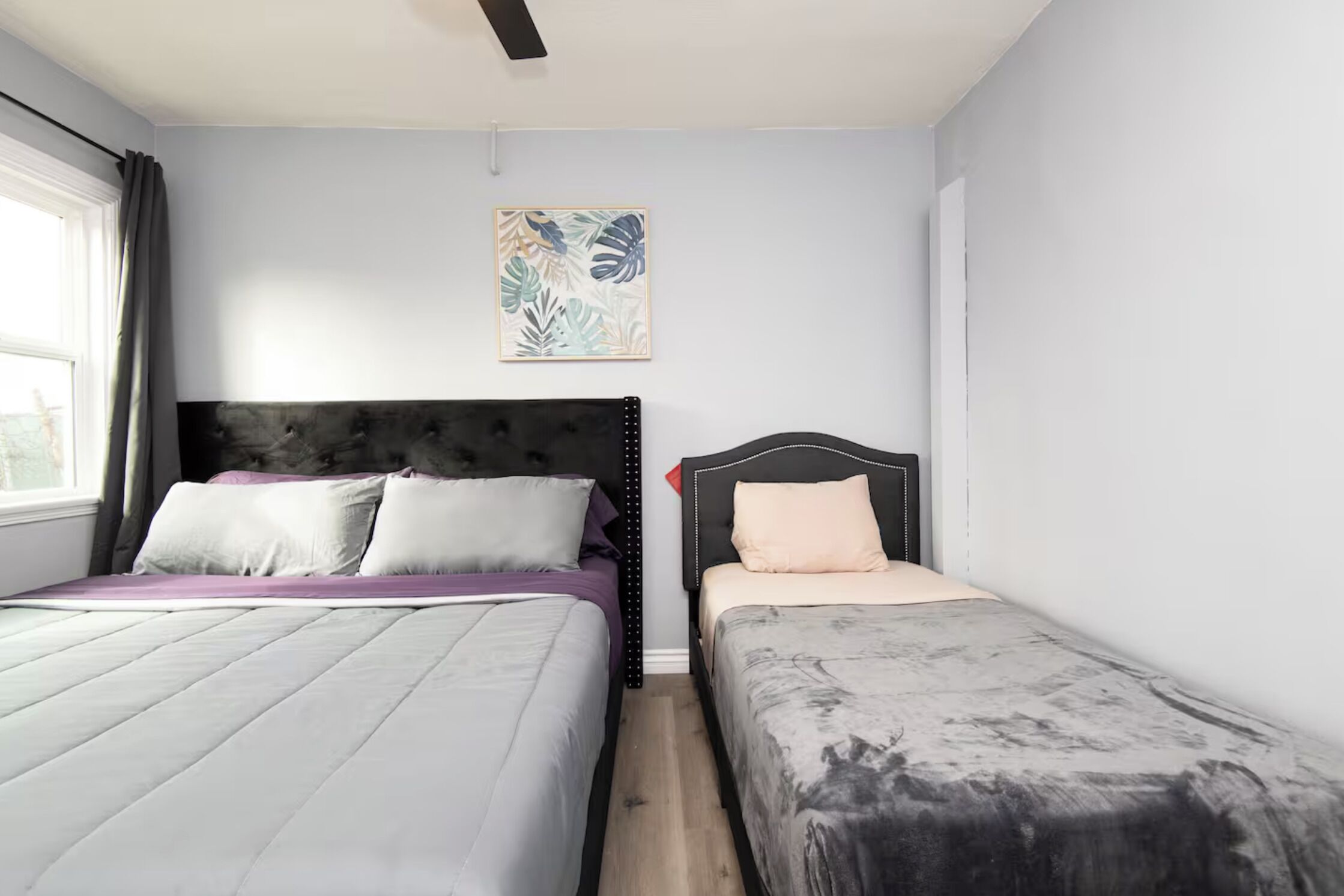 Ein Schlafzimmer mit zwei Betten, einem Deckenventilator und einem Wandbild.