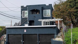 A modern two-story building with a dark facade, a covered porch, and two garage doors.
