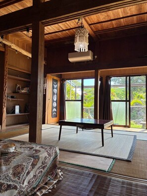 Une pièce avec un plafond en bois, une table, une chaise, une bibliothèque et une vue sur la verdure à l’extérieur.