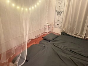 A bed with a canopy, a small bedside table, and a wall with decorative patterns. - Sakamine Furusato-an—Limited to one group per day—A uniquely designed house where traditional warmth and exotic charm come together (喜界町)