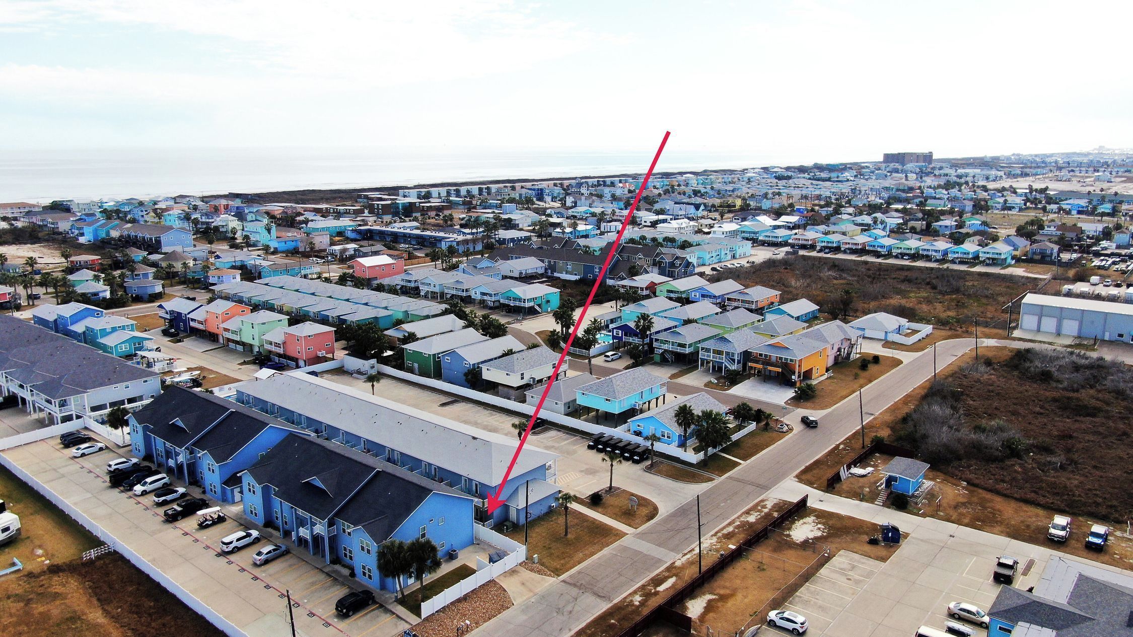 An aerial view of a residential area with houses, roads, and a large blue building.