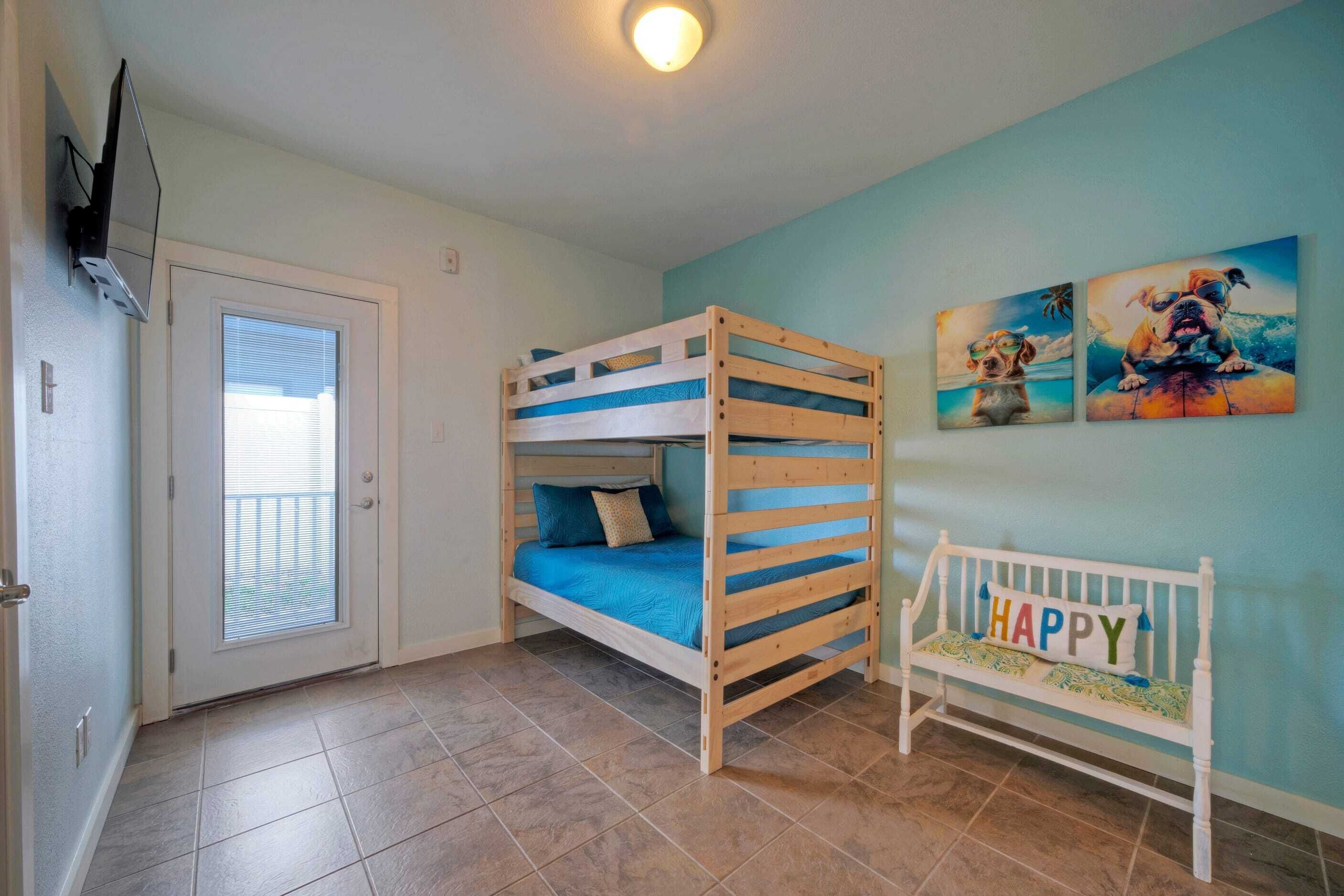 A room with a bunk bed, a door with a view, and a wall with two dog-themed paintings.