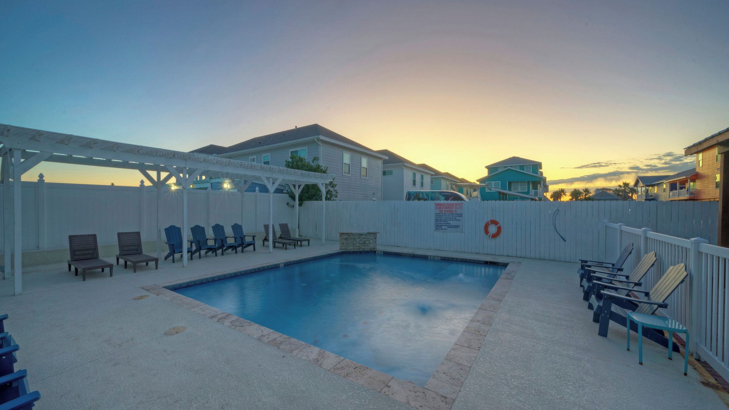 A swimming pool with lounge chairs and a covered seating area.