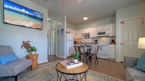 A modern living room with a sofa, a coffee table, and a TV displaying a beach scene.