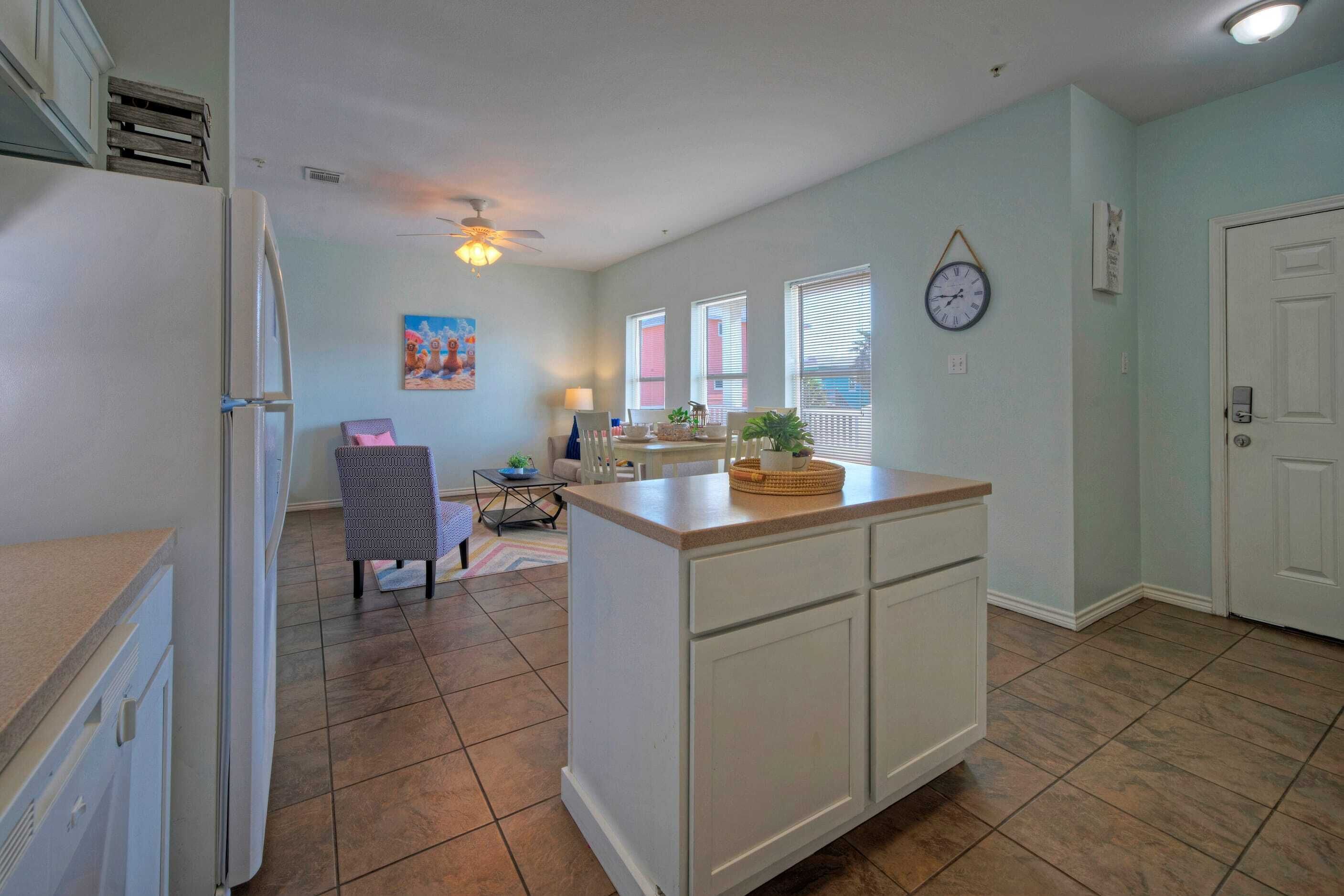 A kitchen with a central island, white cabinets, and a dining area with a table and chairs.