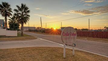 A sign for Costa Bahia Vacation Rentals with a sunset in the background.