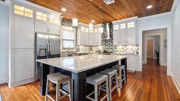 A spacious kitchen with a large island, wooden ceiling, and white cabinetry.