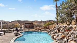 A swimming pool with a stone border, surrounded by rocks and potted plants, with outdoor furniture and a building in the background. - Welcome to Mina Ranch! Steps to Leoness Cellars, minutes to Galway Downs! (Temecula)